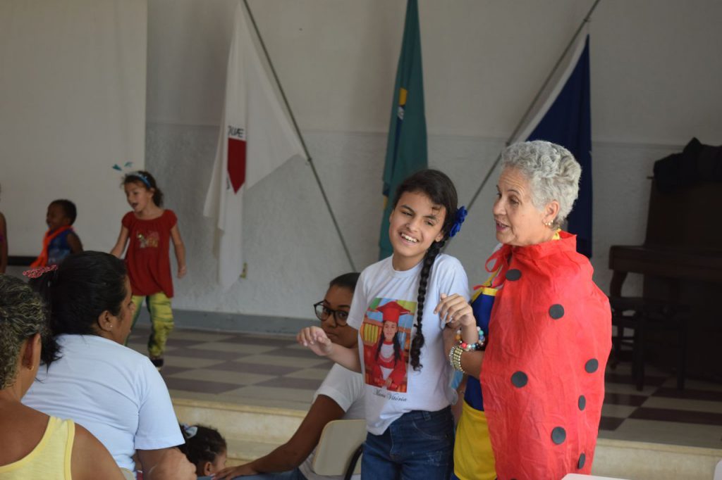 Maria Madalena andando com criança da instituição enquanto conta uma história - Foto: Rafaela Andrade
