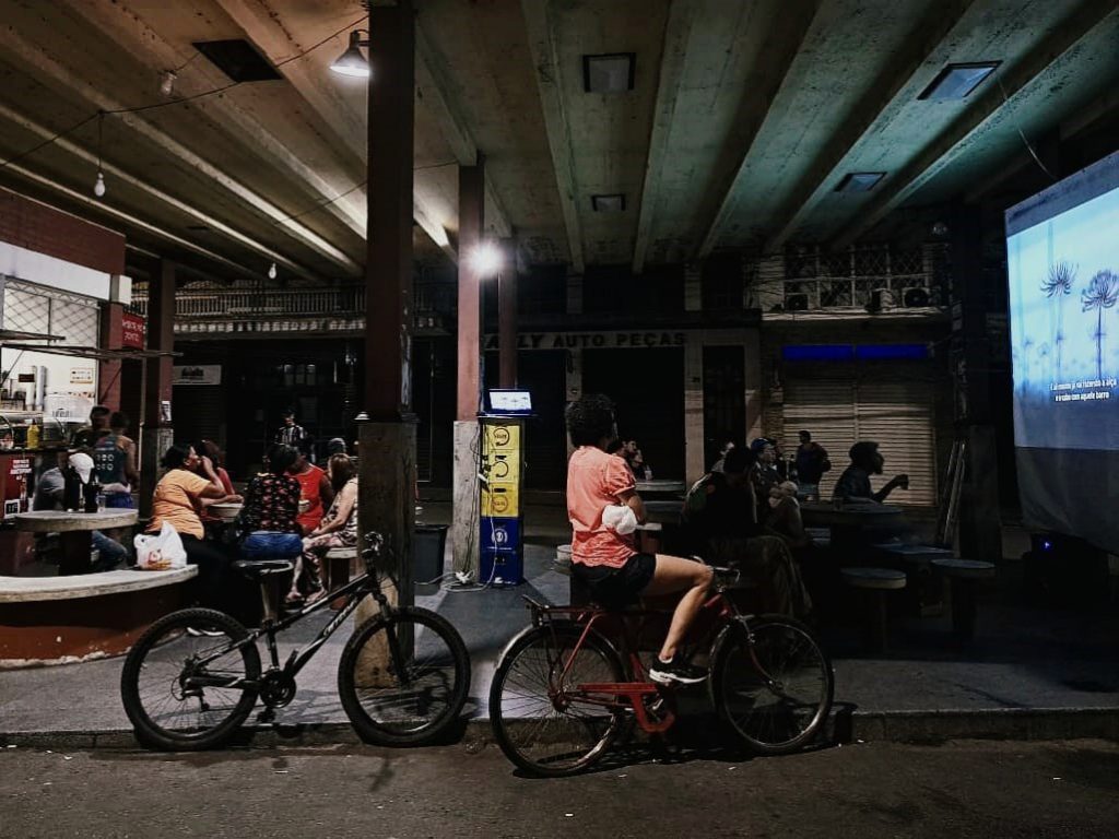 Moradores na rodoviária velha assistindo filme.