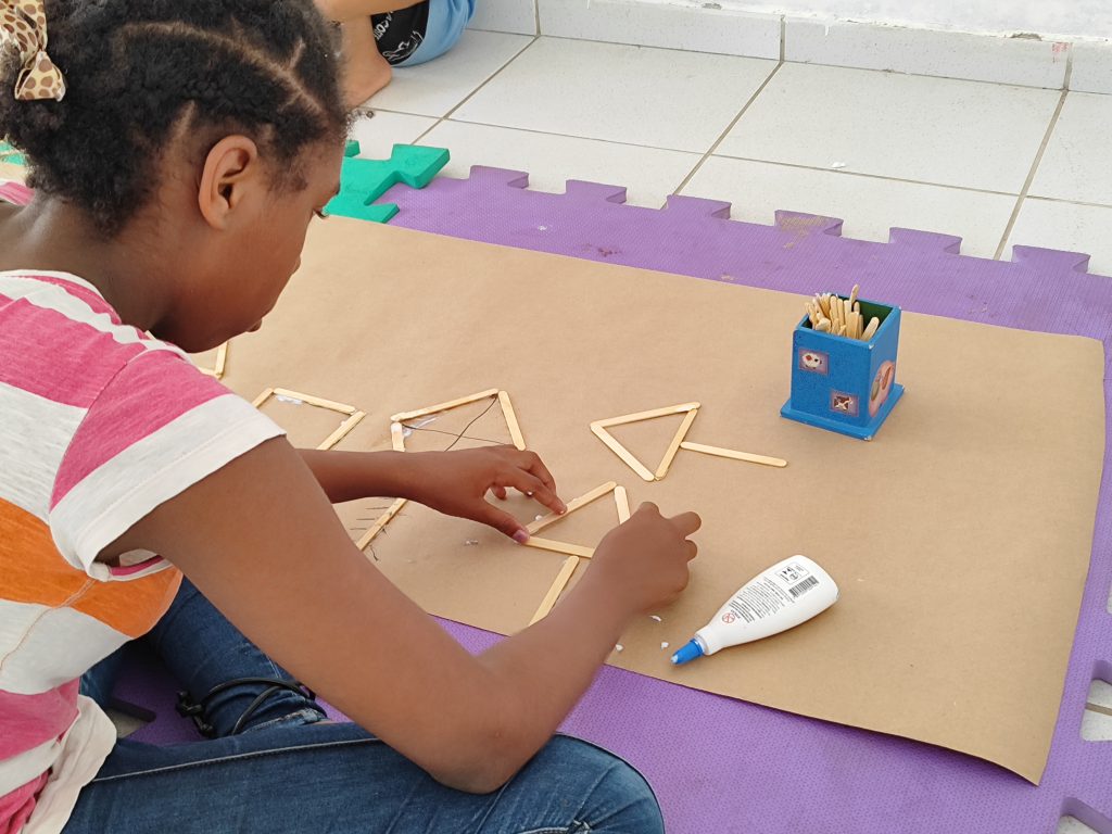 Criança brincando com colagem de palitos. 