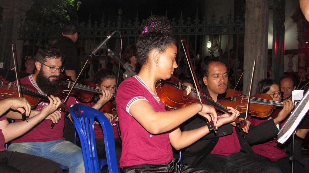 Alunos integrantes da Orquestra tocando violino.